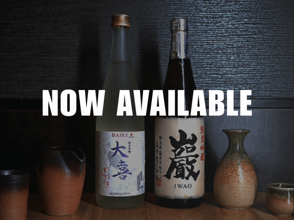 A dark, atmospheric banner featuring Daiki and Iwao sake bottles with Japanese ceramic cups and the text "NOW AVAILABLE" in bold white letters.