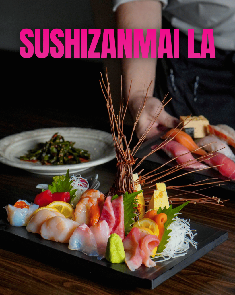 Sushizanmai LA lettering above a sashimi platter with colorful garnishes, with nigiri sushi in the background.